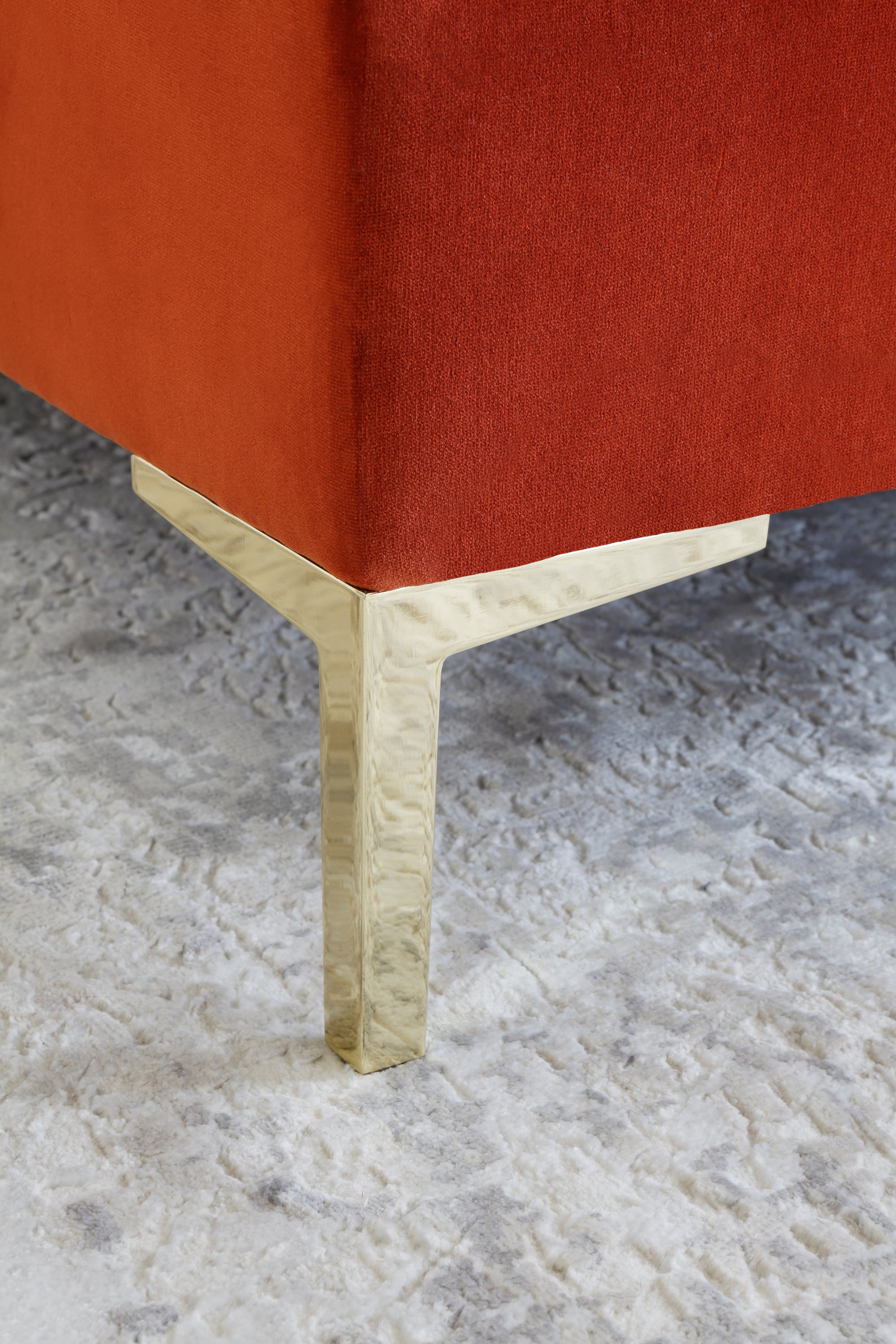 A close-up of one metal angled leg in a gold finish