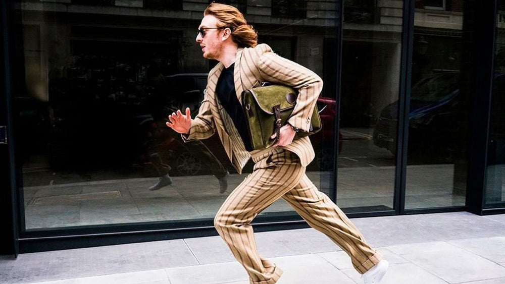 A man wearing dashing tweeds and running in the city