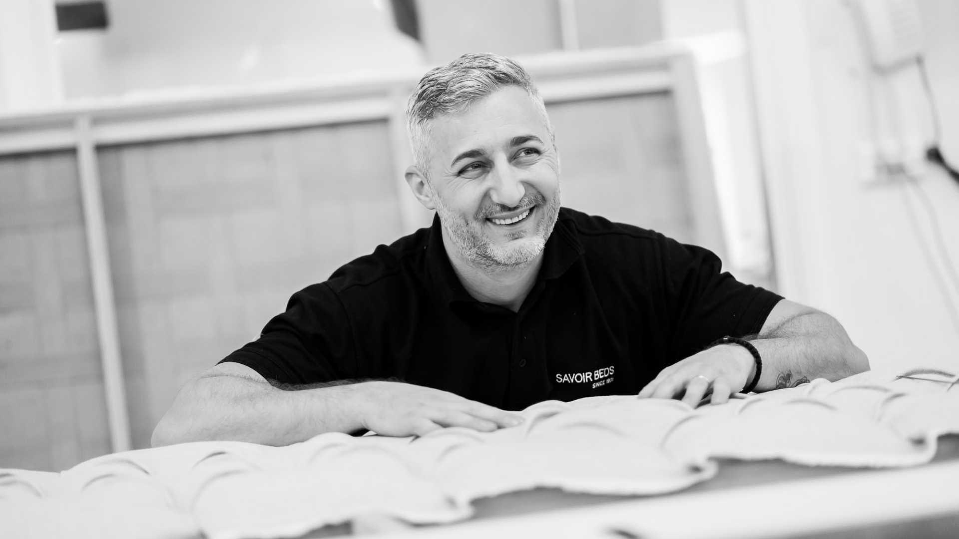 A Savoir craftsman working on a bed and smiling
