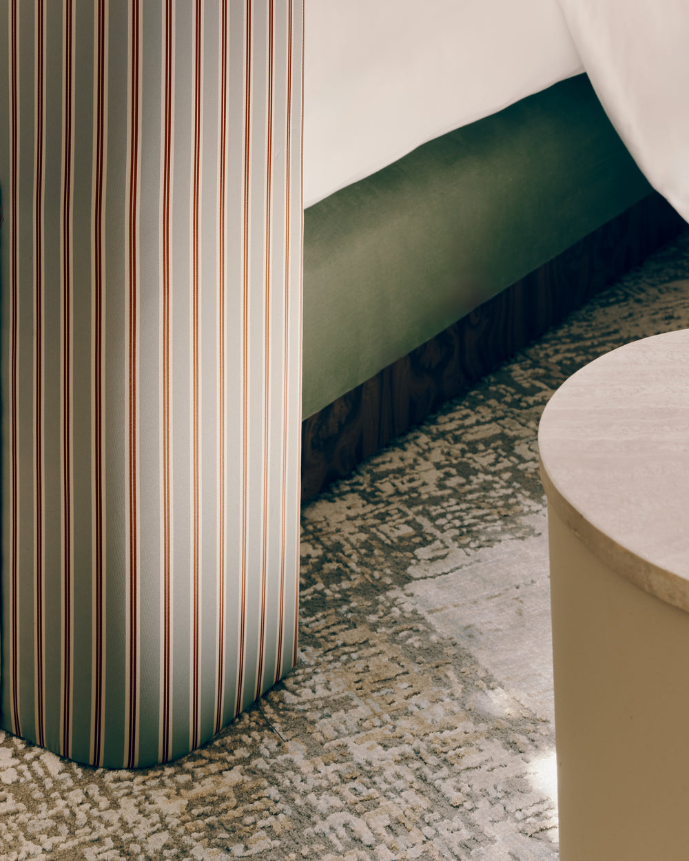 Corner detail of the back of Hugo headboard upholstered in stripe satin fabric