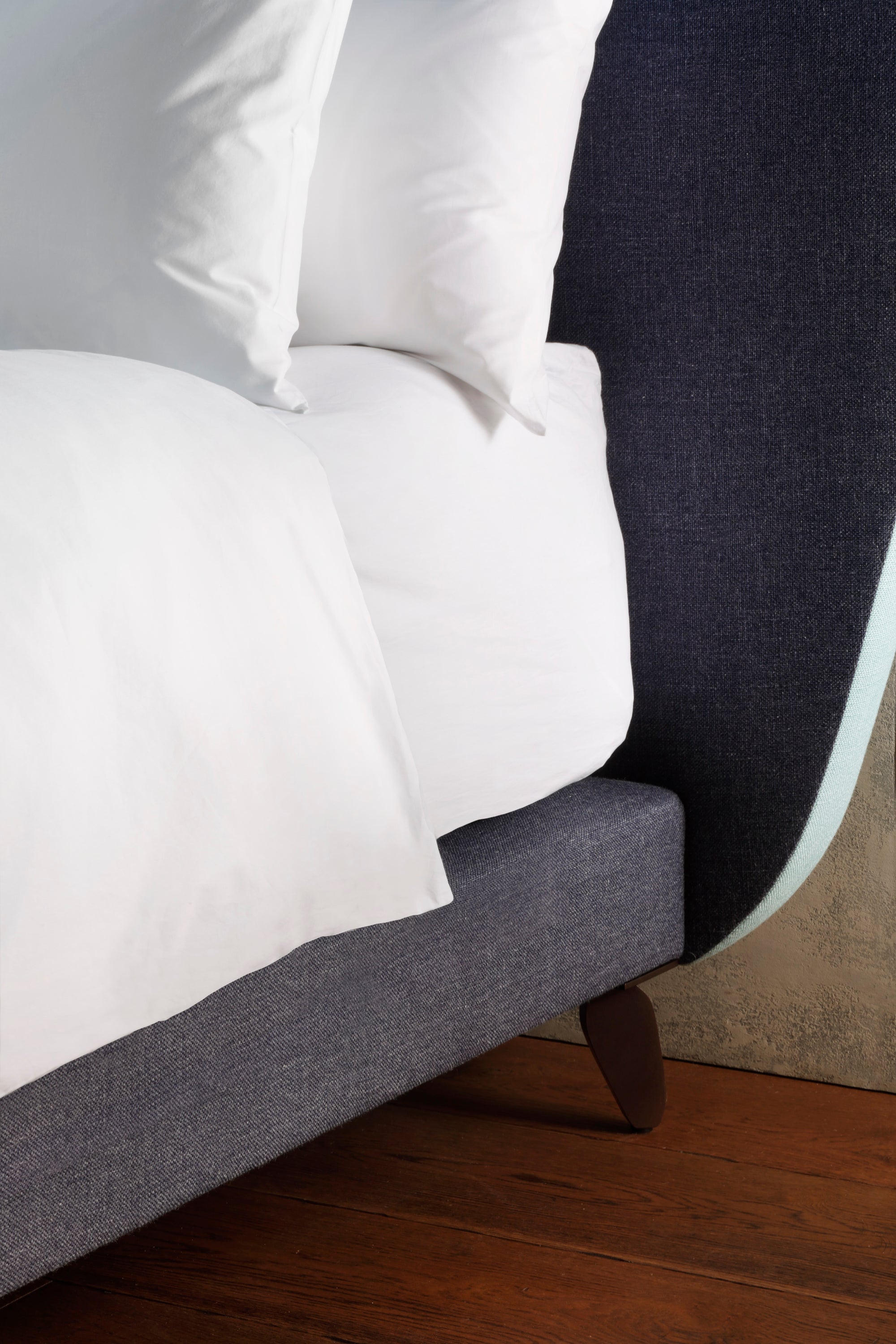 A close-up of the Cloud headboard and a Tom Faulkner leg in a nickel finish