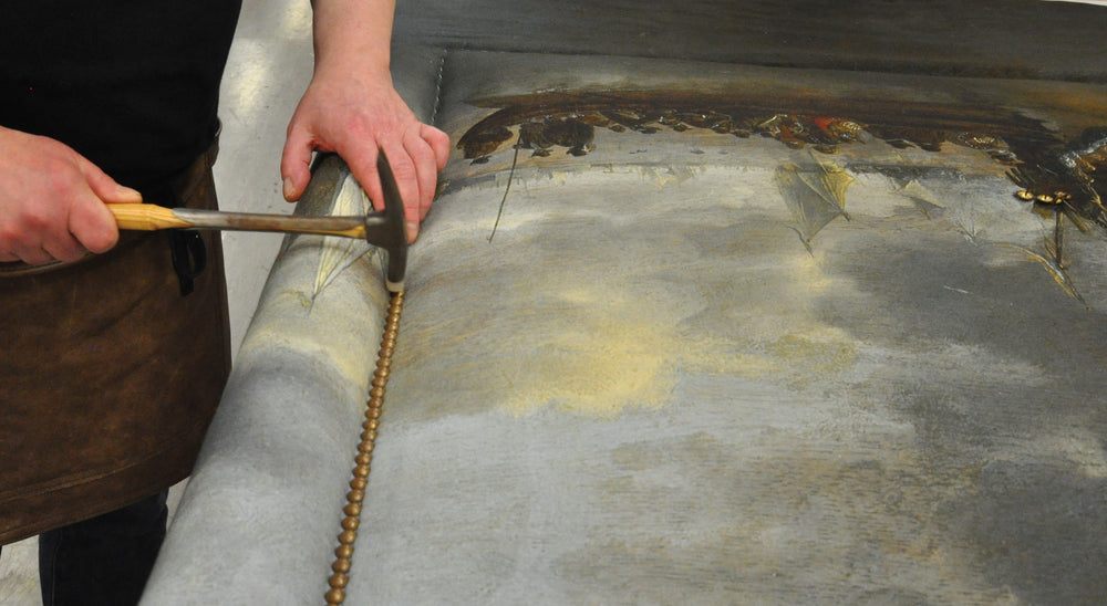  Old gold speckle nailing is applied by a Savoir craftsman to the Felix headboard.