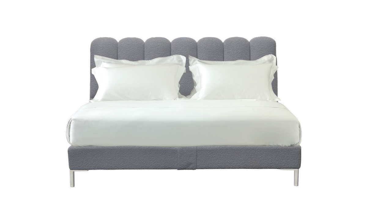 A modern gray upholstered bed frame with a scalloped headboard and matching base, shown with white bedding and two white pillows on a plain white background.