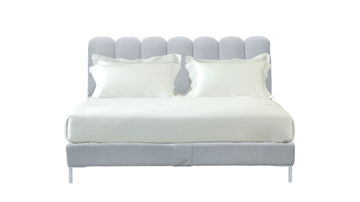 A light gray upholstered bed frame with a tufted headboard and matching footboard, shown with white bedding and two white pillows on a plain white background.