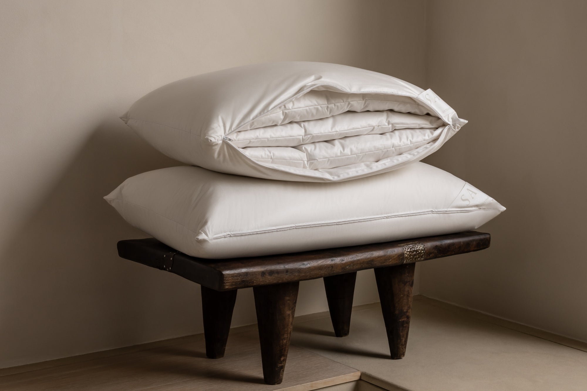 stack of 2 Savoir multi-tension pillows on a small bench