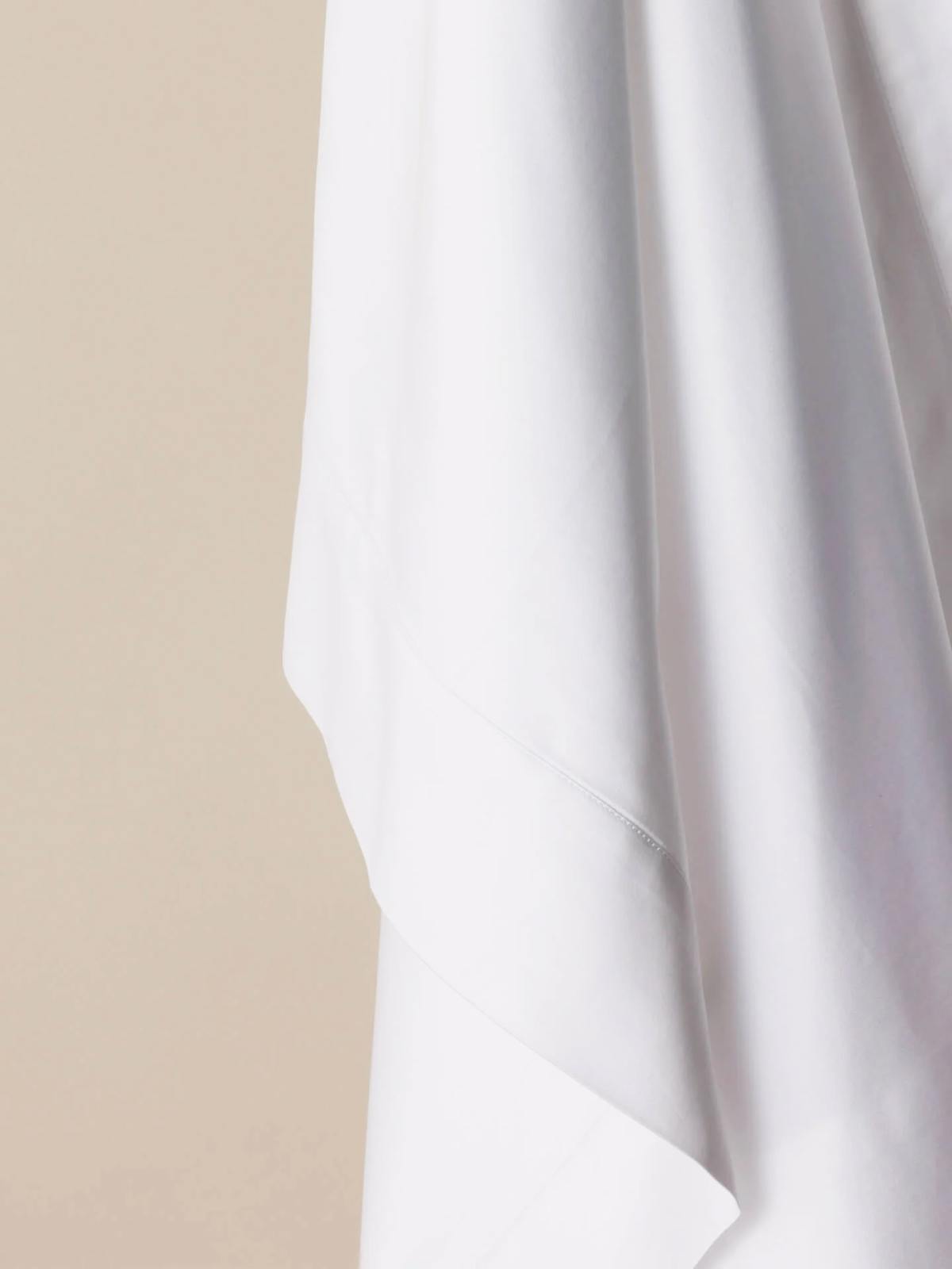 Savoir sateen bed sheet photographed up-close against a beige background.