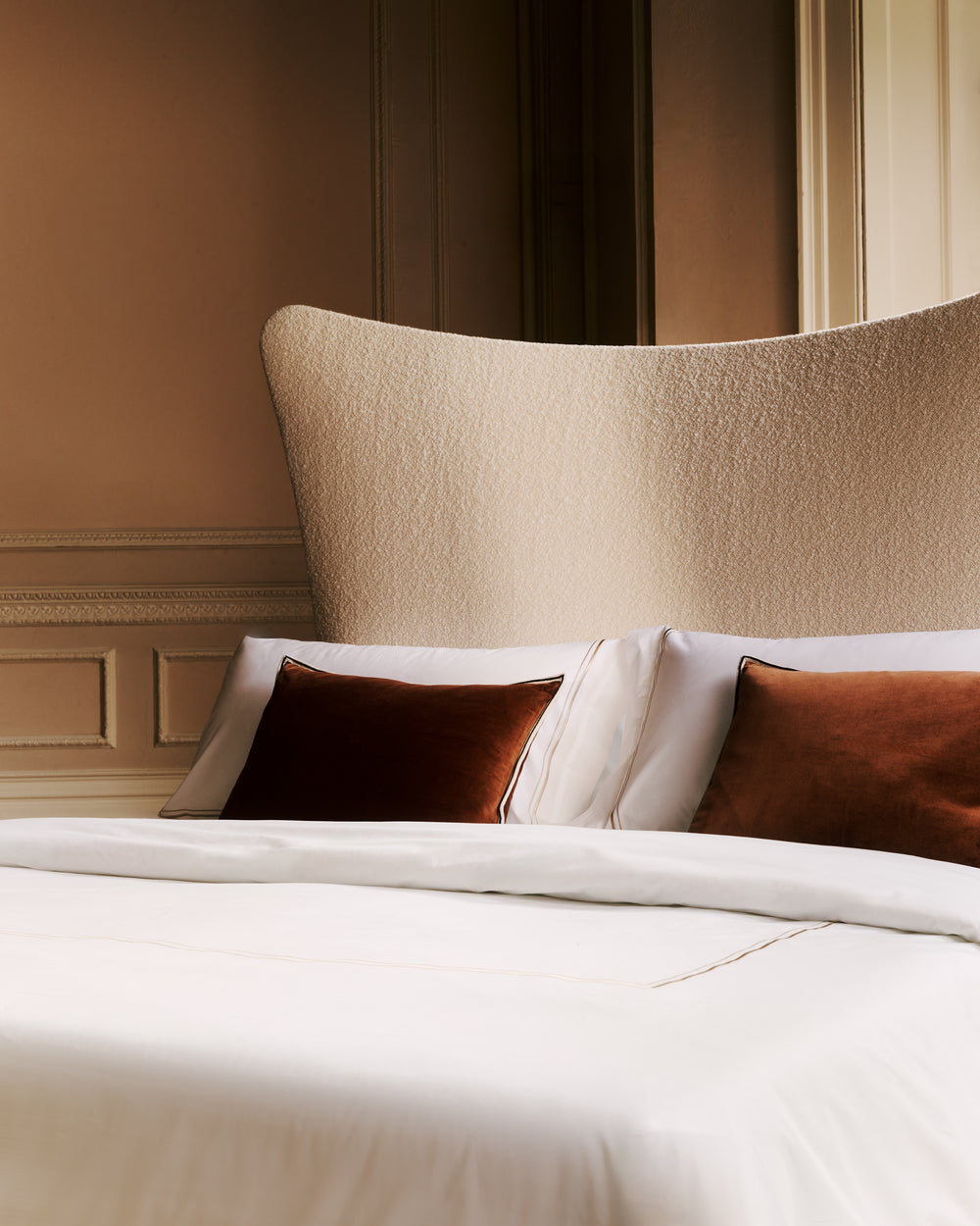Close-up of the Amelia bed with pillows and a textured headboard in a bedroom setting.