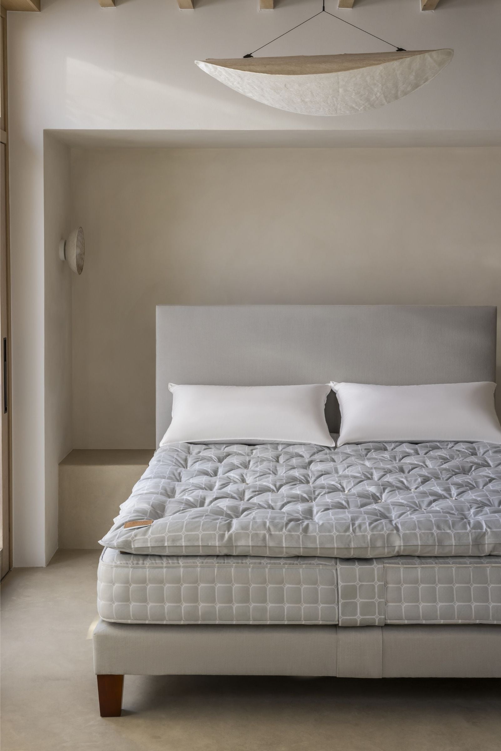 Bed with gray mattress and topper in a minimalistic bedroom setting