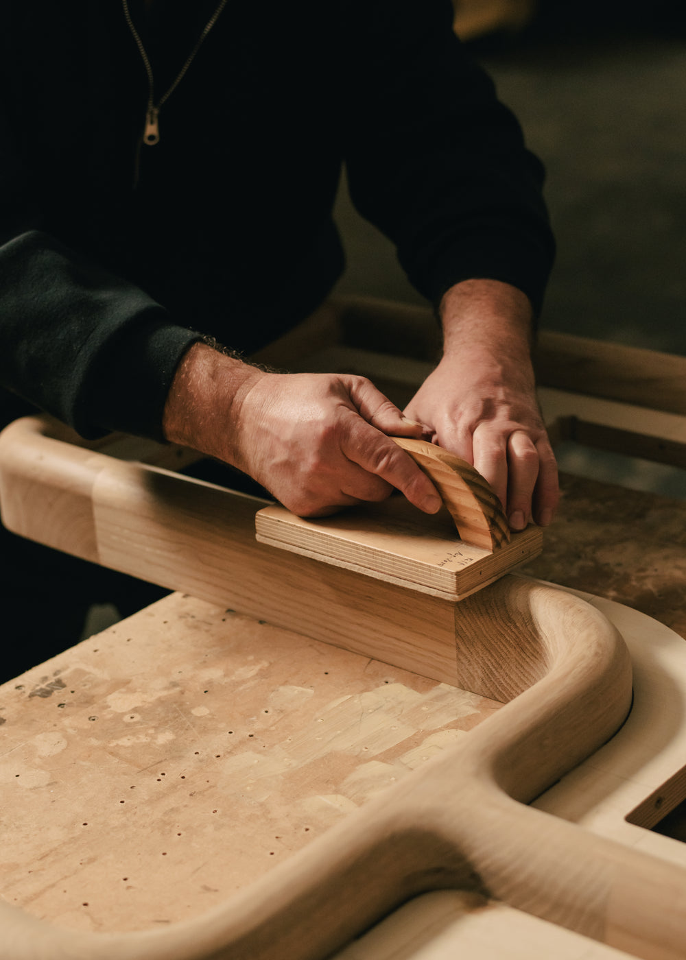 Savoir artisan sanding a wooden surface with a sanding block