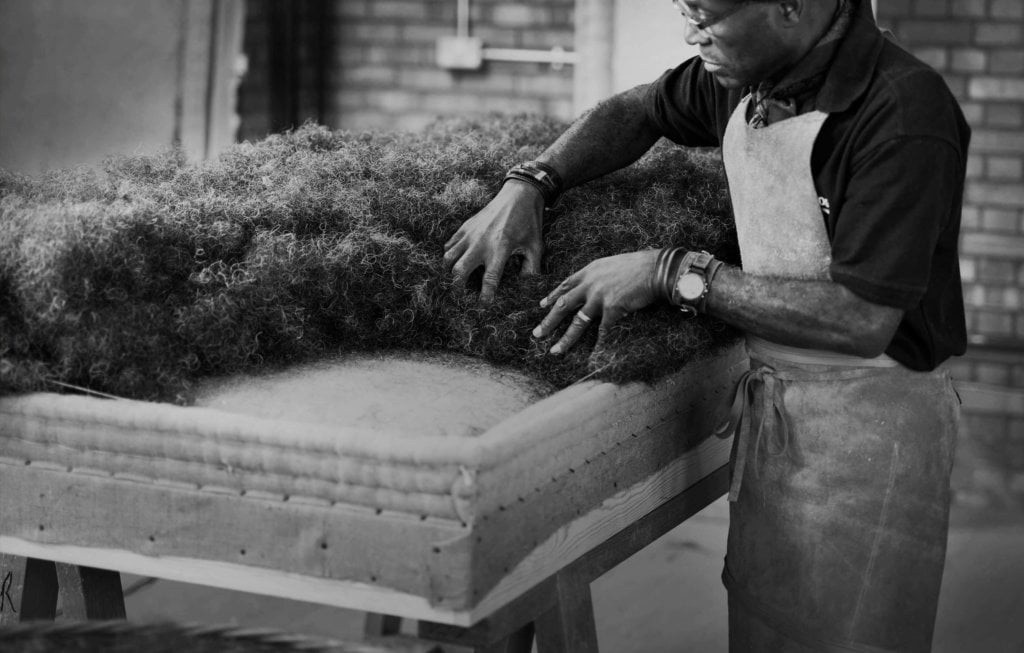 A Savoir craftsman delicately putting horse hair on a base
