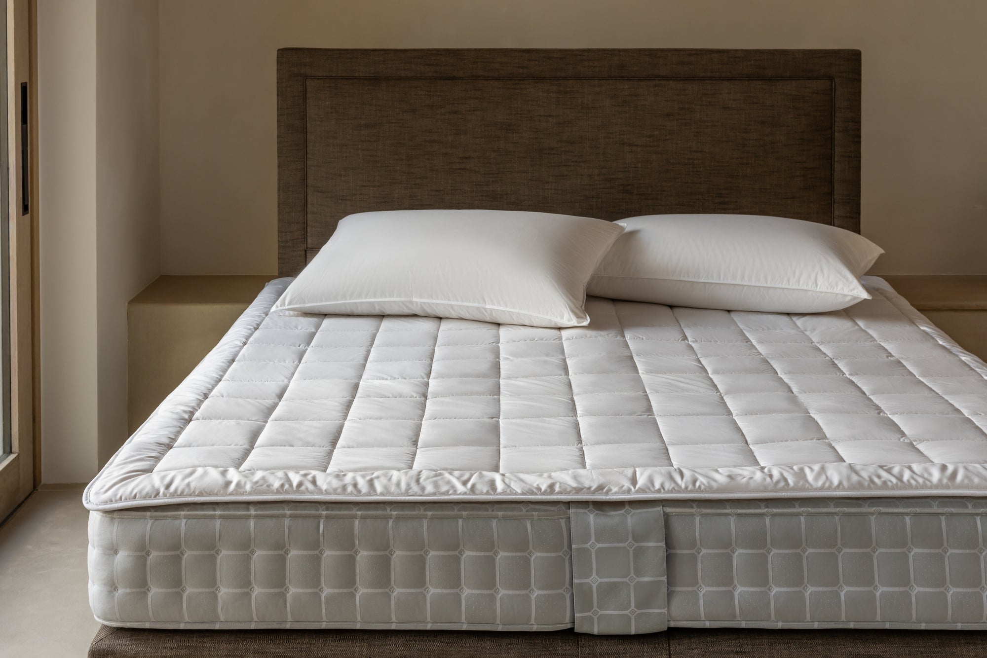 Wool mattress protector on Savoir bed with two pillows