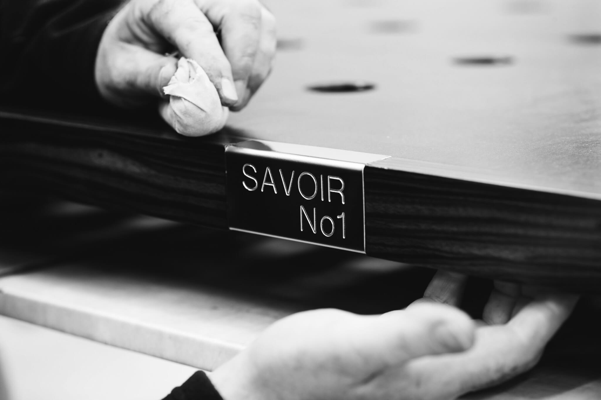 Image of a craftsman hand polishing the Savoir No 1 plaque attached to one of the luxury custom beds