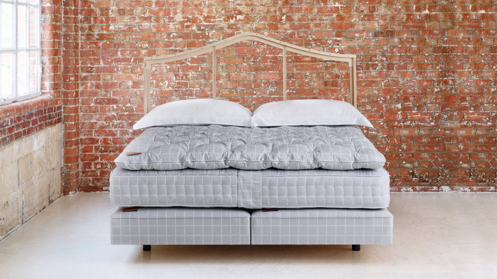 Image of a naked Savoir No3 bed, showcasing a deep mattress and base and a topper, all adorned in the signature Trellis ticking pattern
