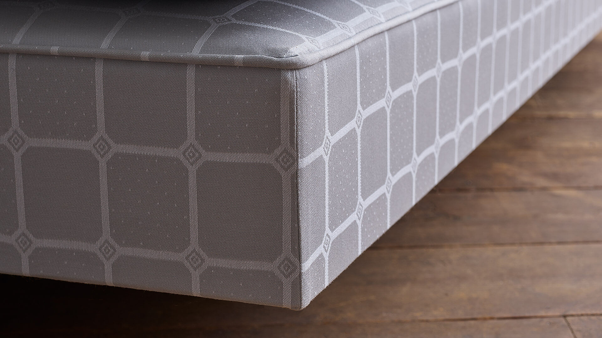 Closeup image of a box spring corner, adorned in the iconic Trellis ticking pattern