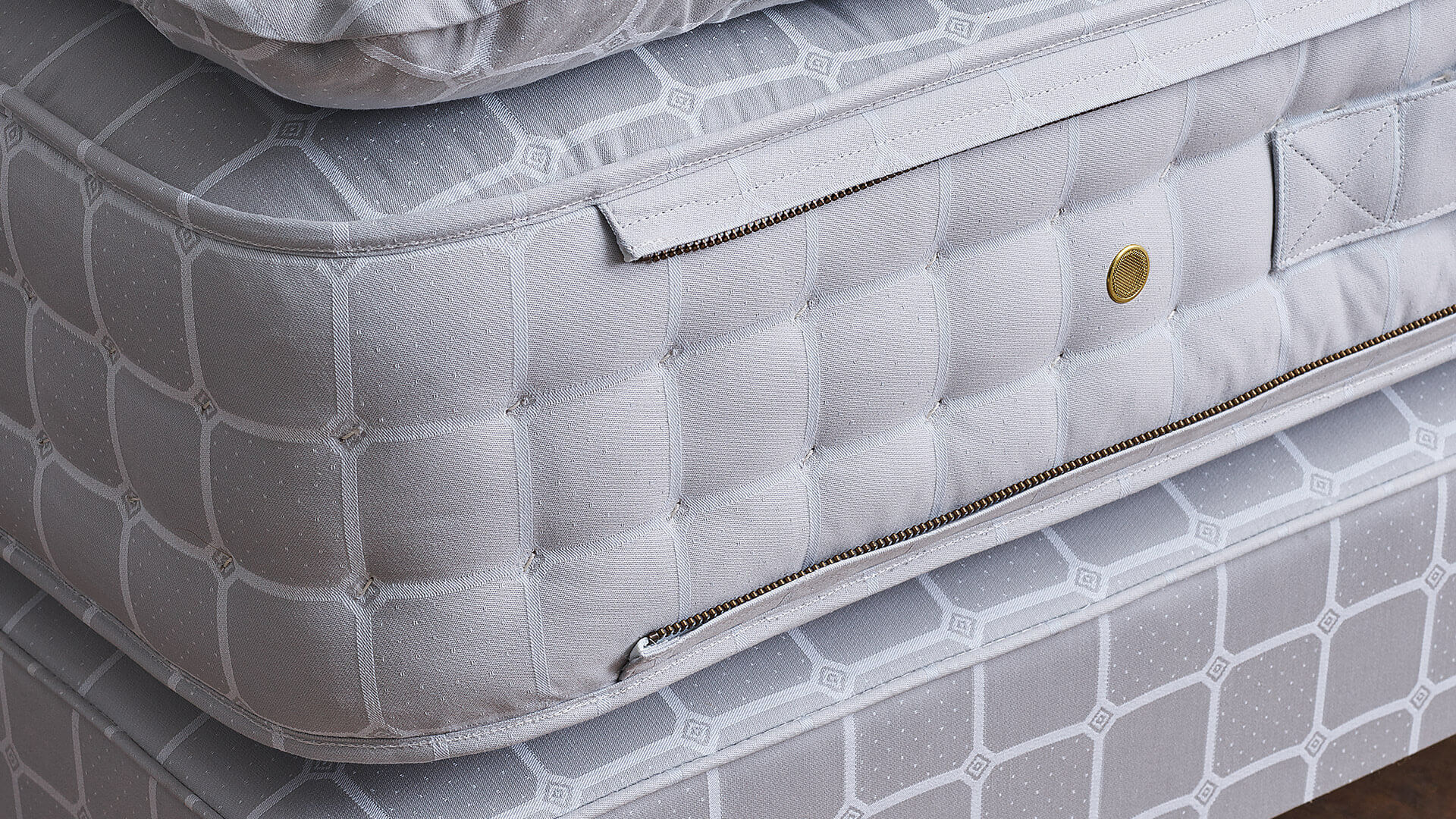 Closeup of the side of a mattress, showcasing the side zip and gold vents, all handmade at Savoir Bedworks