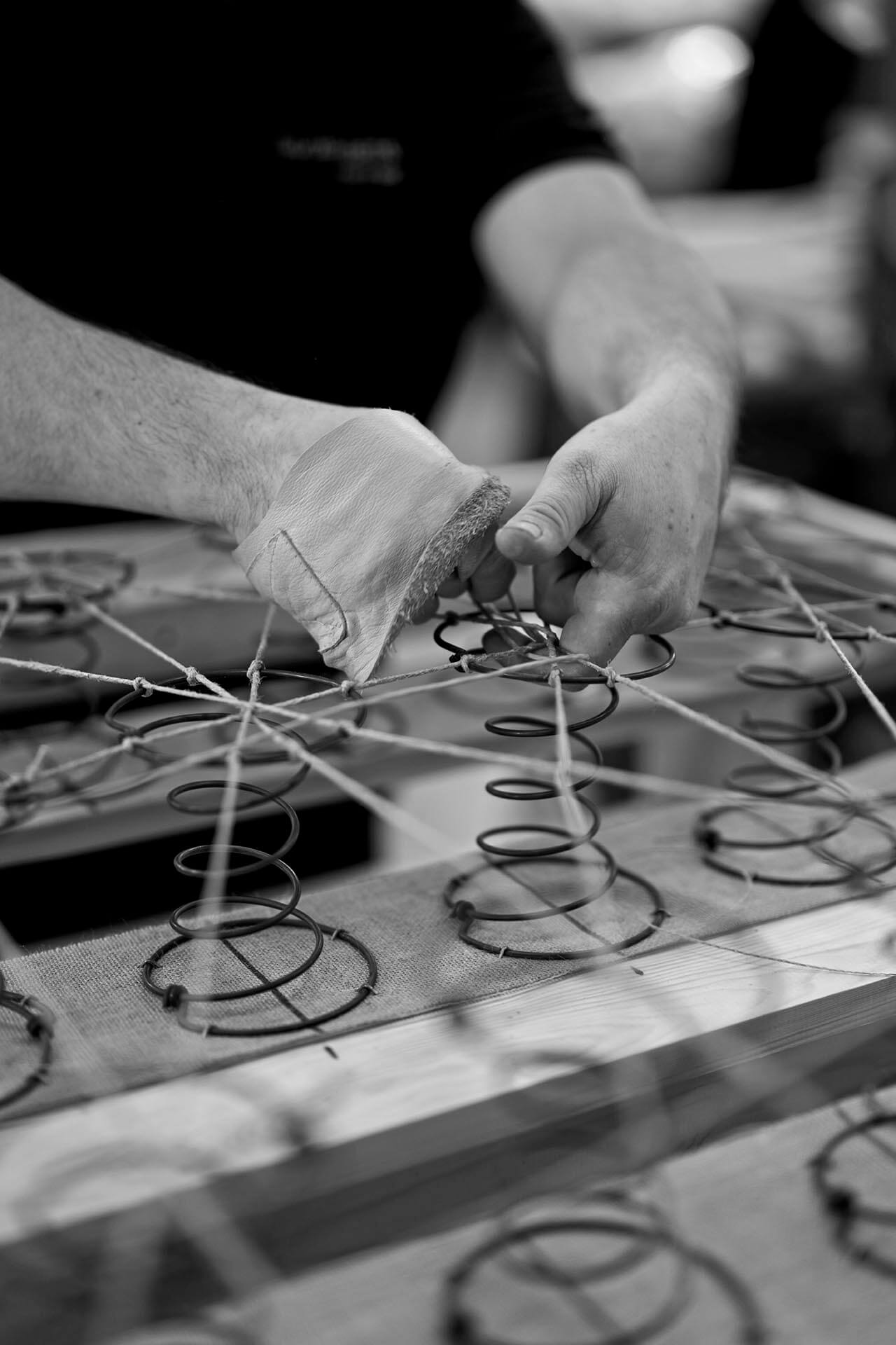 An image showing a craftsman hand tying the hourglass springs in a base