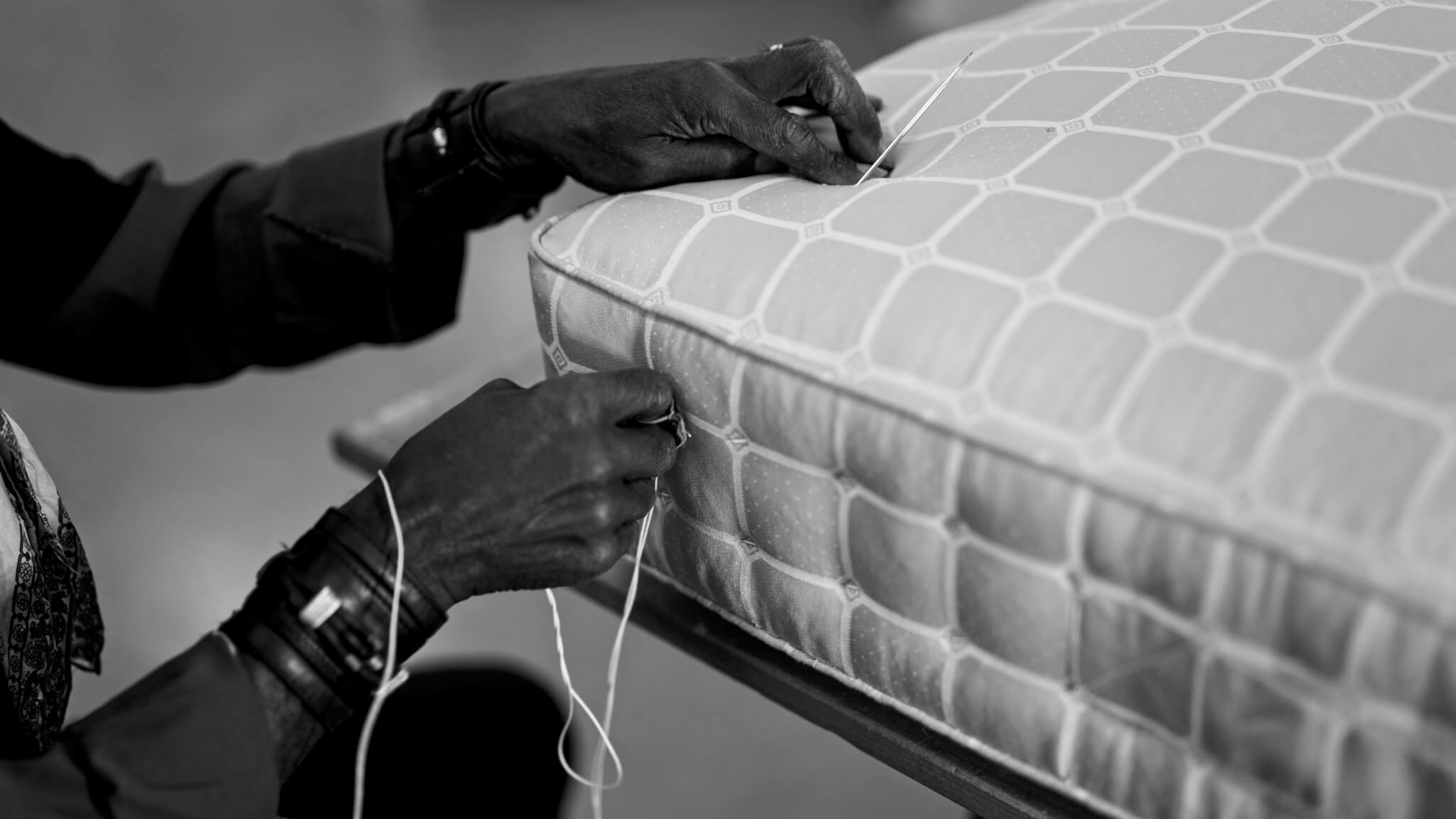 A craftsman hand slipping a mattress, a traditional technique used to make a mattress