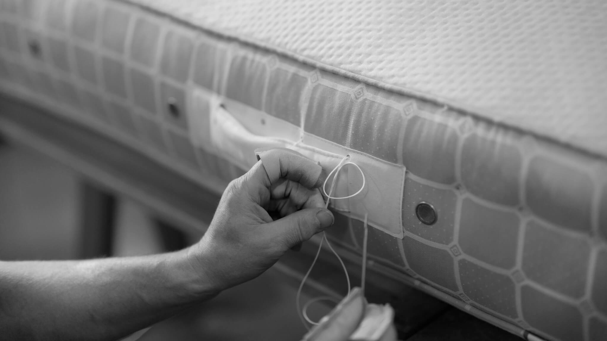 A Savoir craftsmen stitching the handles onto a mattress