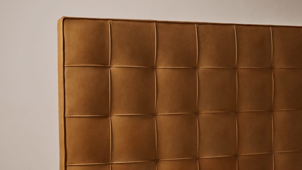 A close-up image of the Savoir Winston headboard featuring beautifully textured natural leather in rich, cognac tone.