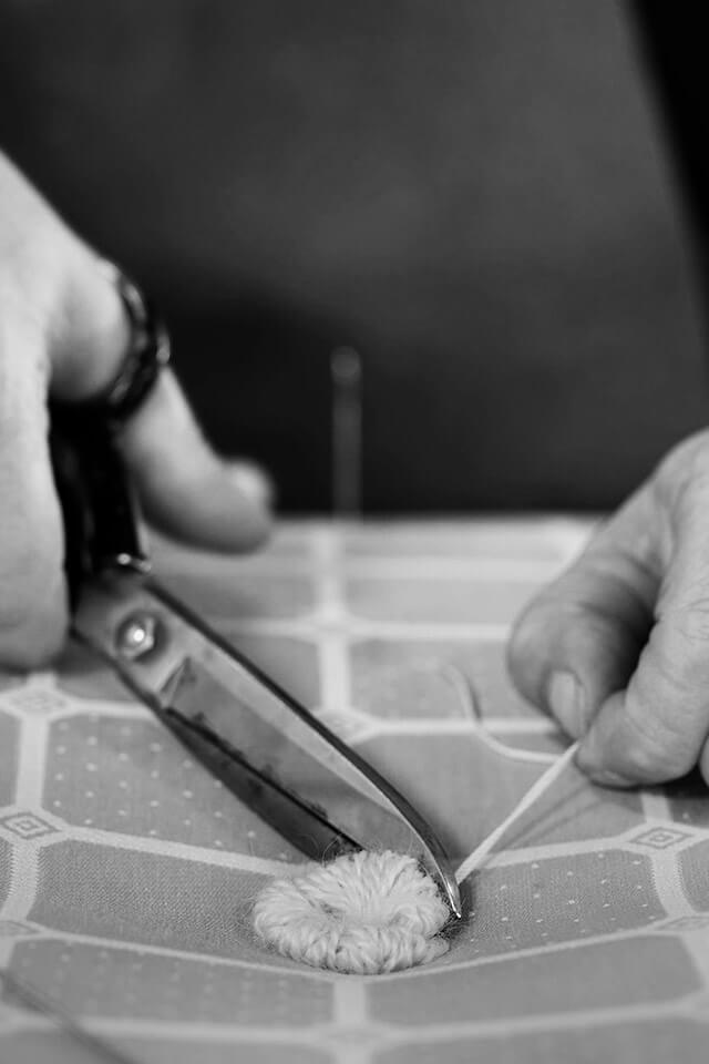 Black and white image of a tuft, used on a Savoir topper, adorned in the iconic Trellis ticking pattern