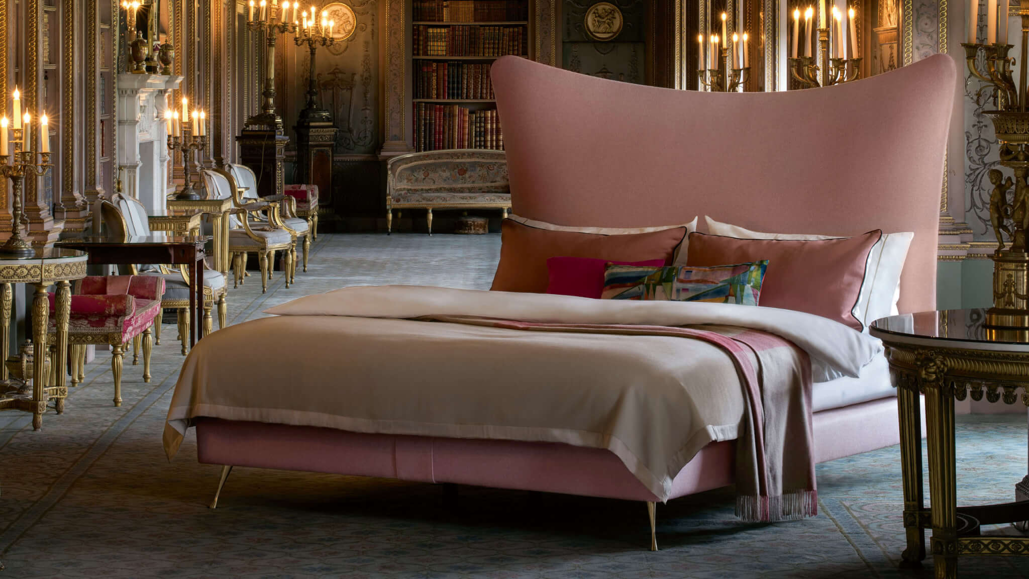 Closeup of the Amelia bed, which features a curved headboard in pink wool fabric, photographed at Syon House in London