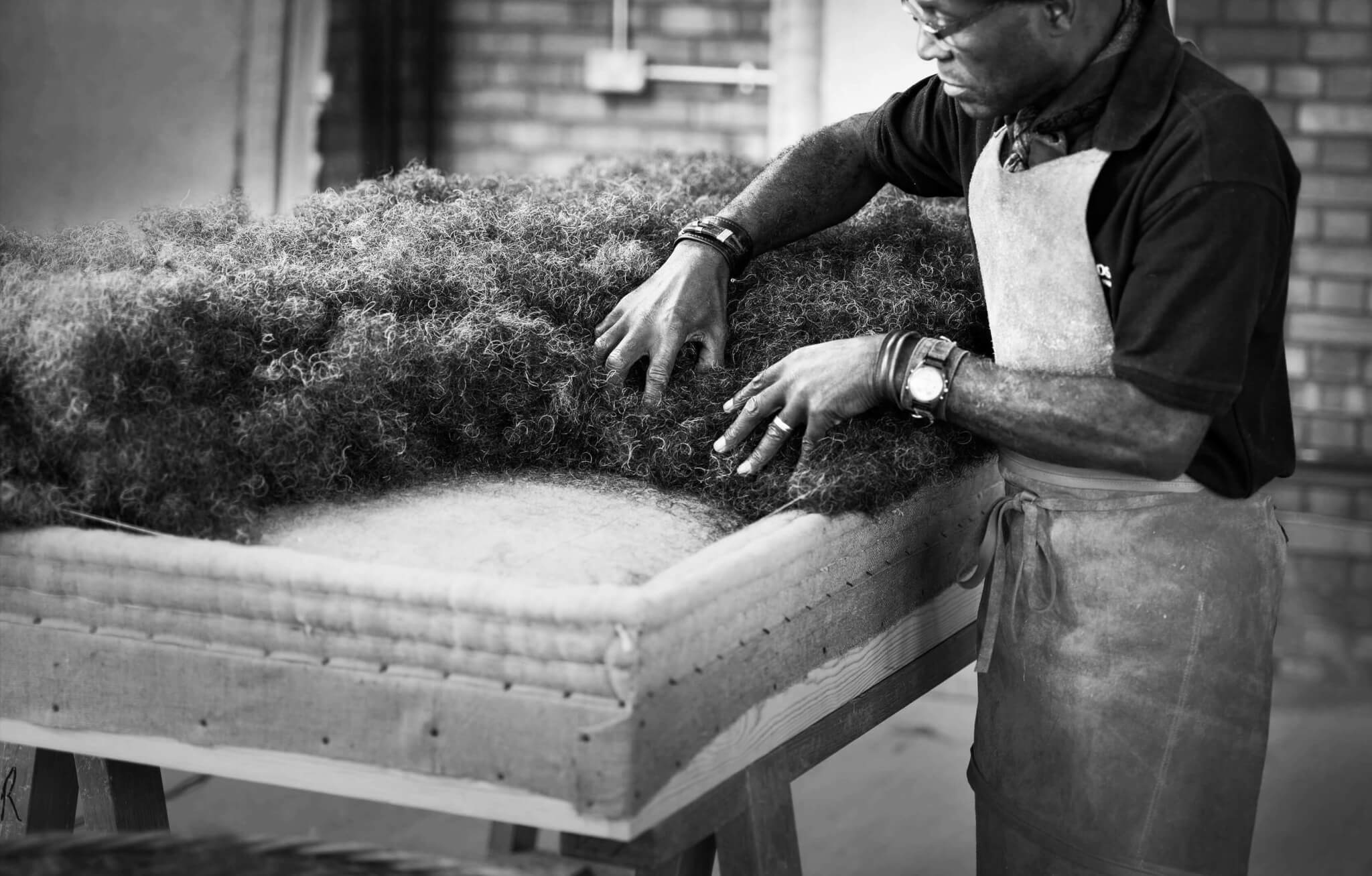 A craftsman laying out the hair on a box spring base. The quality and craftsmanship applies on all beds, right up to our custom Emperor sized beds.