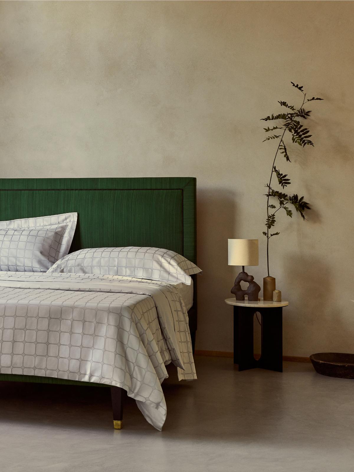 Image of Savoir bed linens in signature Trellis ticking pattern in silver, photographed against a moody backdrop.