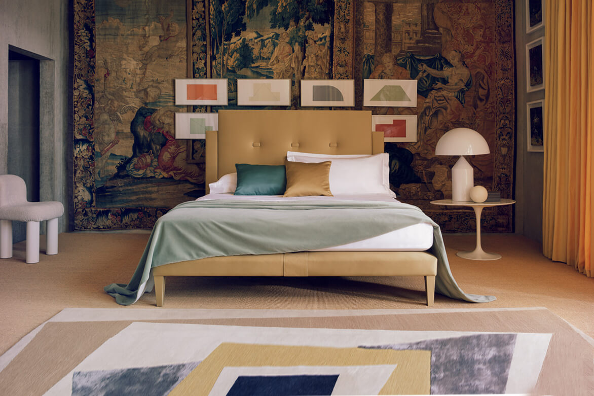 The Savoy bed in gold in a modern home with old rugs on the walls