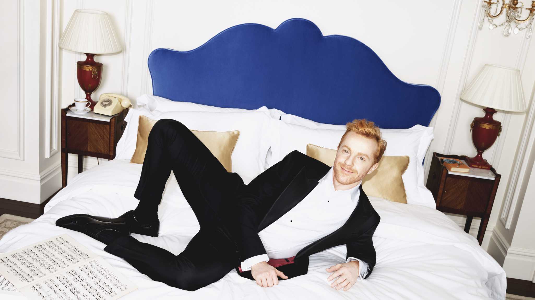 A man laying on a Savoir bed wearing a suit.