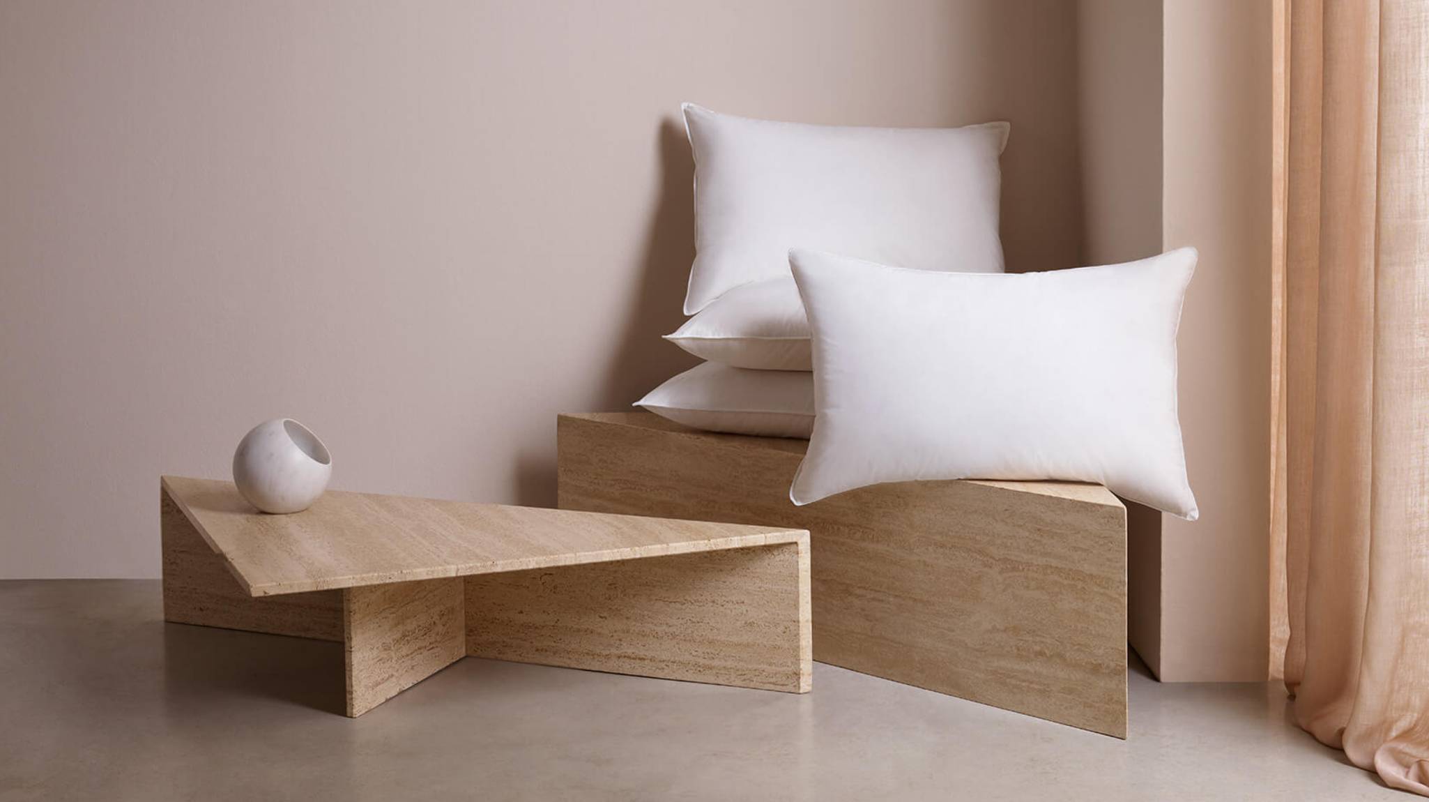Image of our Siberian white pillows photographed in a minimal setting with oak wood tables and pale pink background