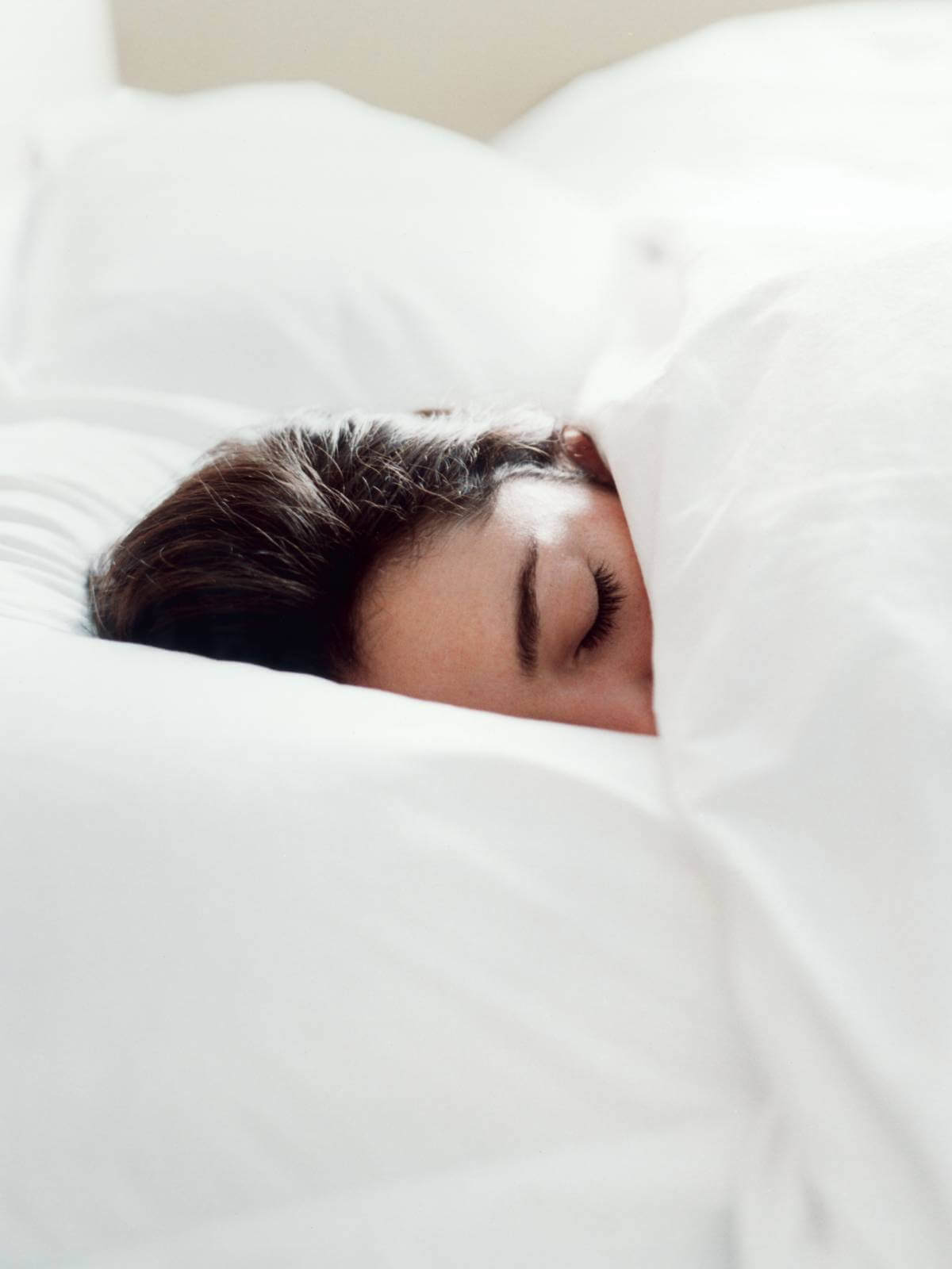 Woman sleeping in a bed dressed in crisp white bed linen