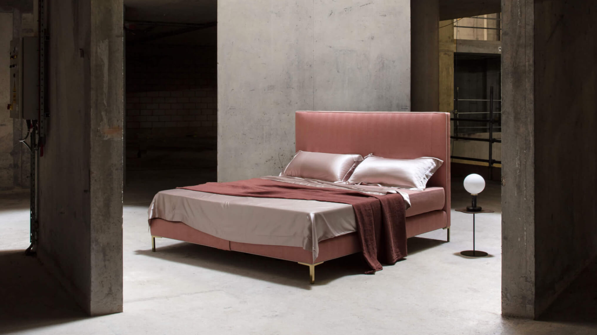 Harlech bed in pink textured upholstery photographed in a brutalist setting