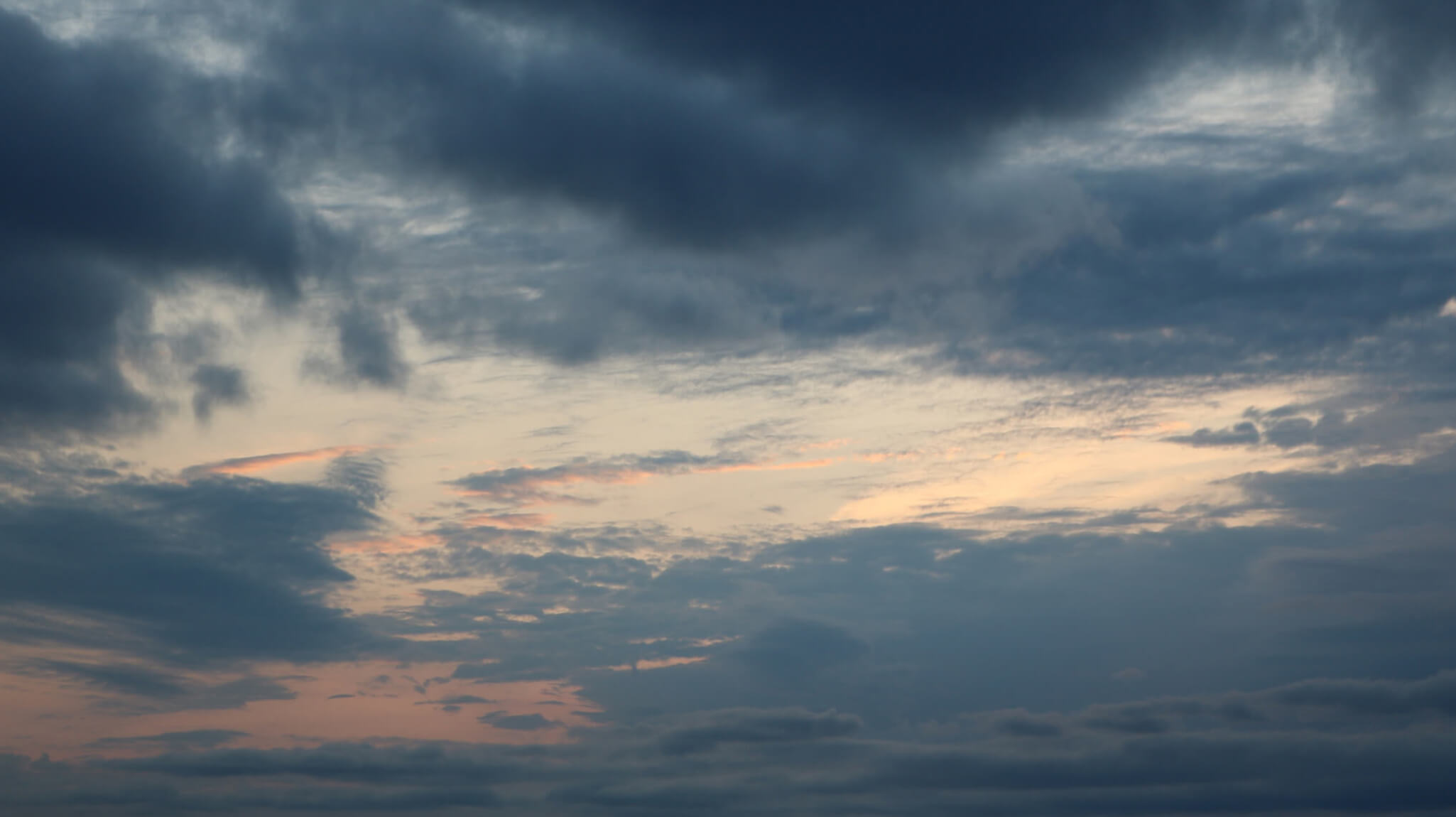 Image of a colourful sky with dark clouds and a sunrise peeking through the clouds