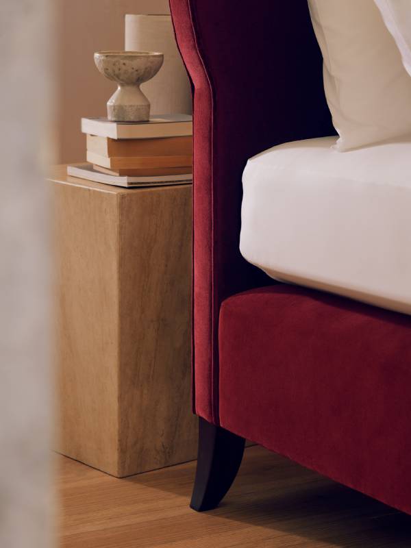 A close-up image of the Elly bed showcasing the Holly leg in Rosewood and the deep ruby upholstery