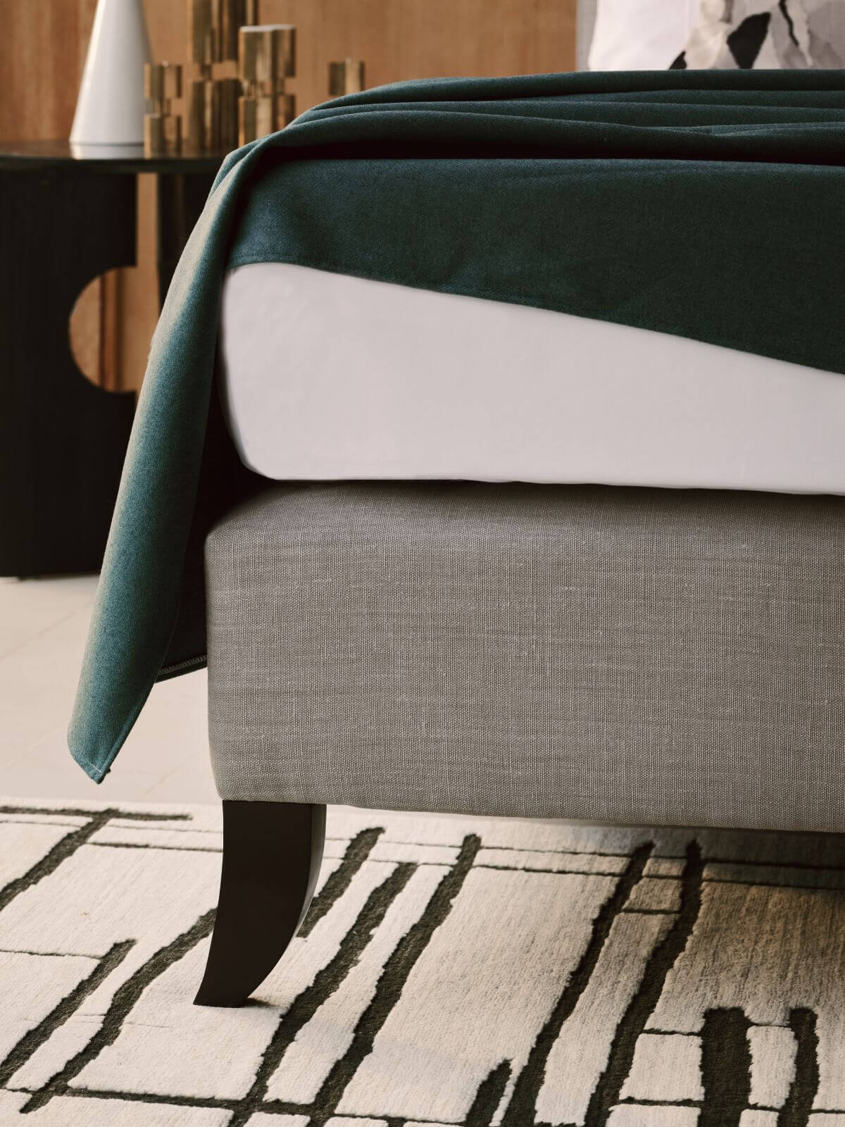 A close-up image of Holly's base, upholstered in Mark Alexander's organic grey linen, standing on a white carpet with abstract black lines