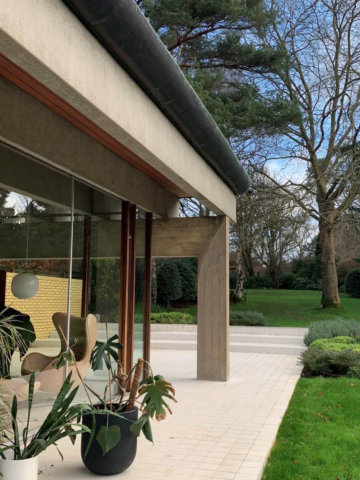 Image of the outside of Ahm House, showcasing brutalist features combined with soft timber detailing in signature mid-century modern style