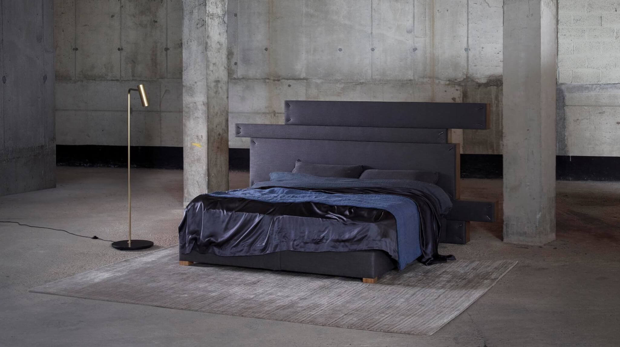 A dark navy bed with a modular headboard, dressed in dark navy bedding that complements the upholstery.