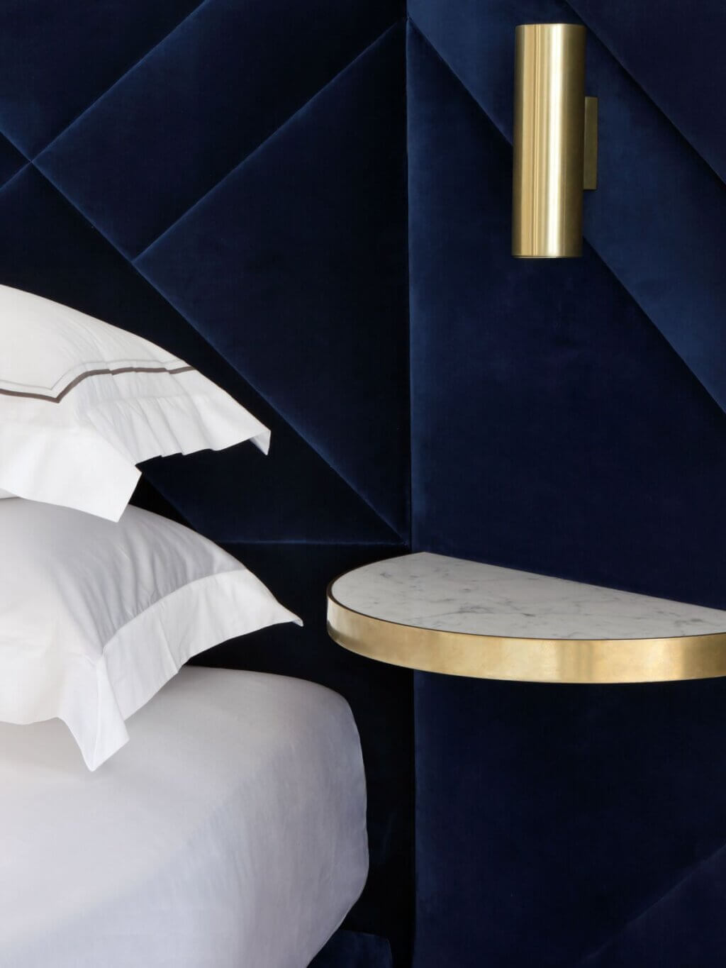 A close-up image of the Rocco design, upholstered in decadent deep blue velvet, with brass gold details and marble finishes