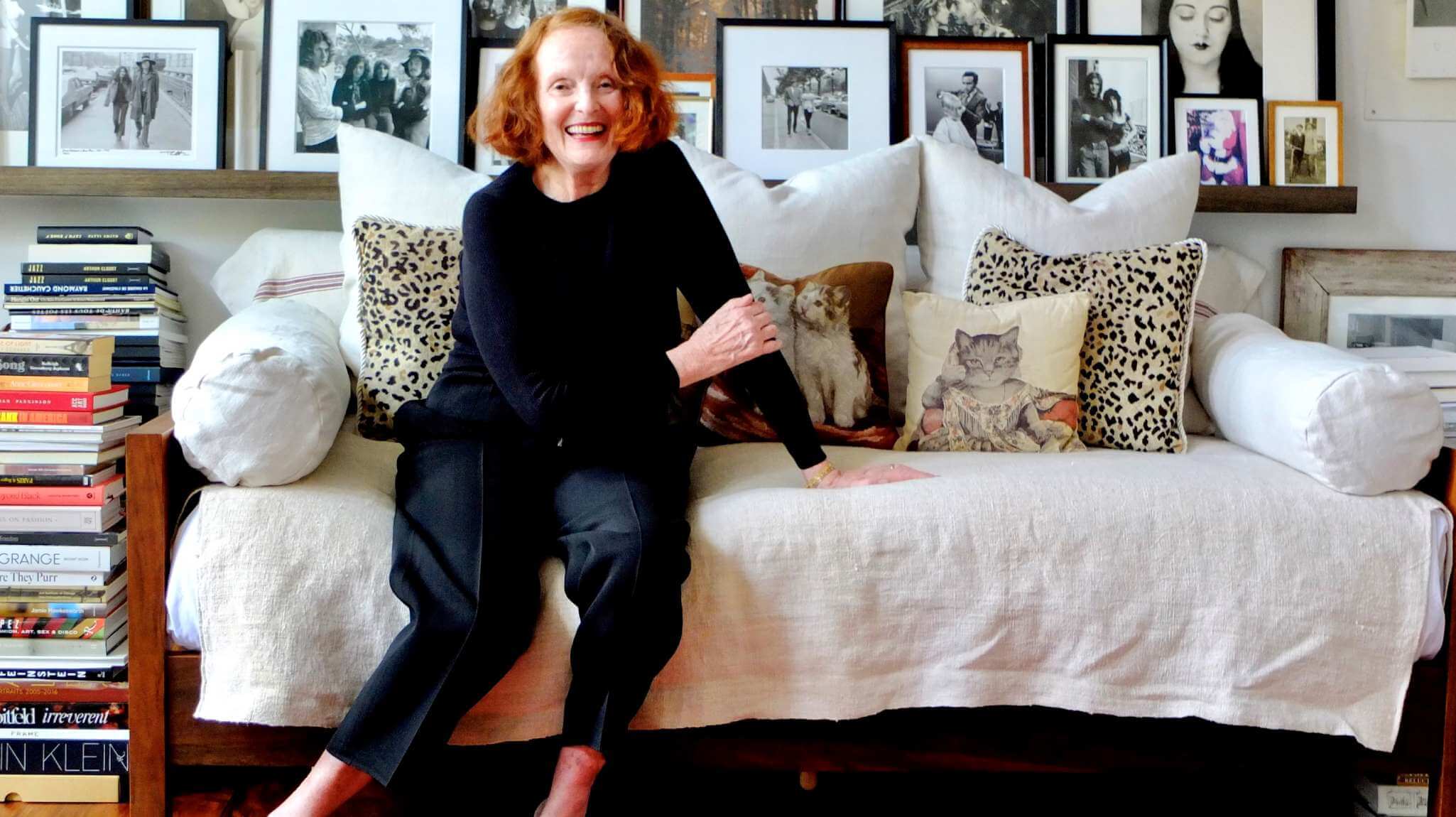 Image of Grace Coddington on her bed and Savoir mattress, wearing all black attire with her cat Jimmy