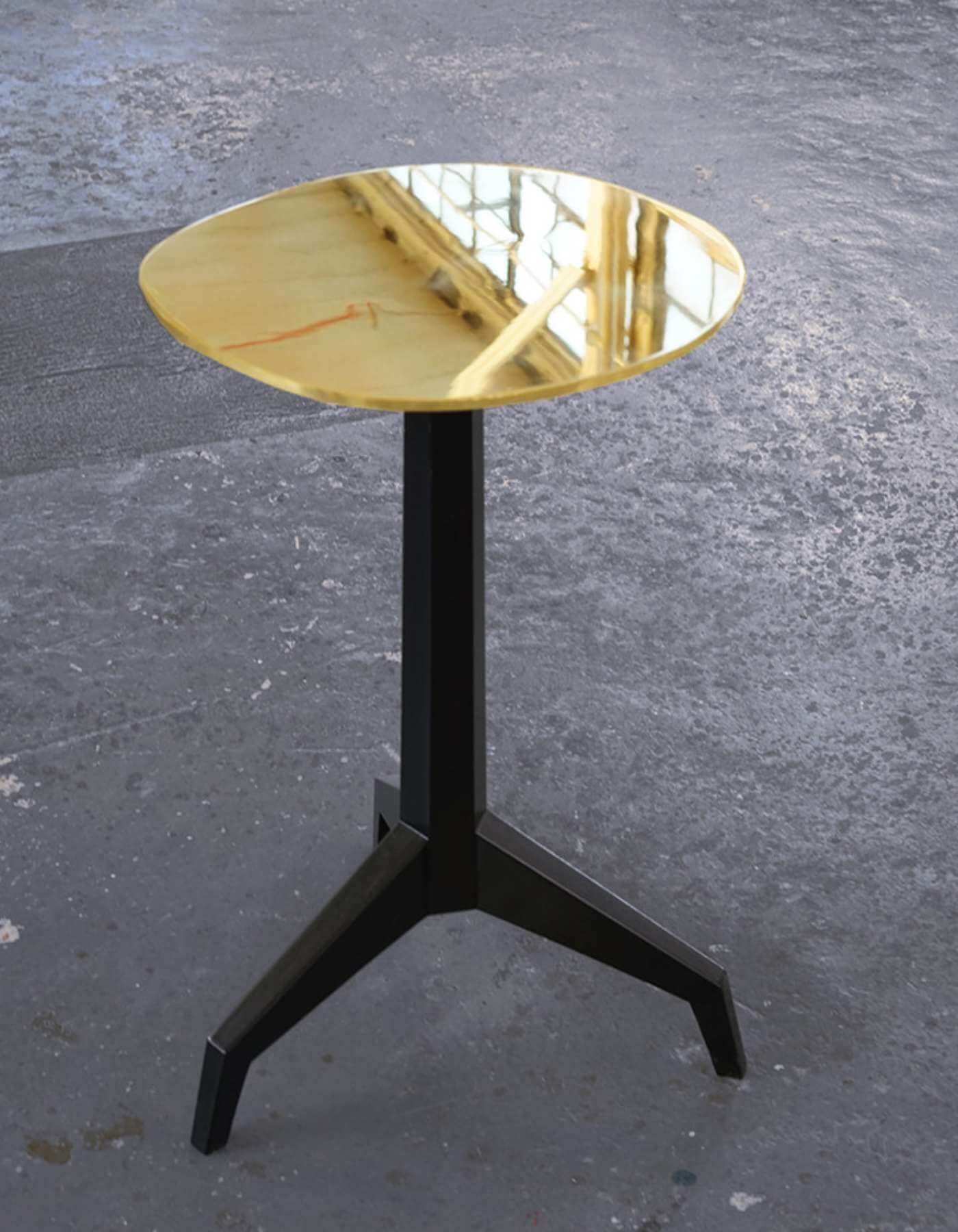 Image of a small coffee table designed and created by Roman Thomas, featuring a black metal frame and a shiny gold top