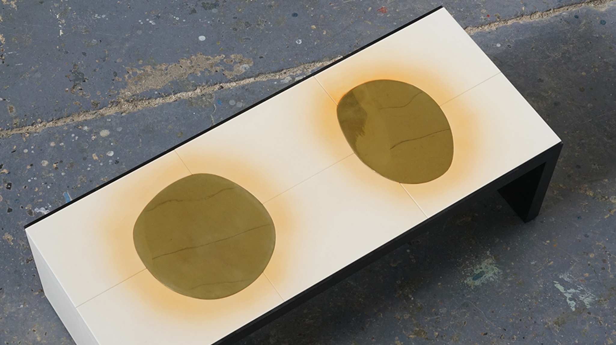 Image of a handmade table by New York-based Roman Thomas, featuring gold brass accents on a white surface