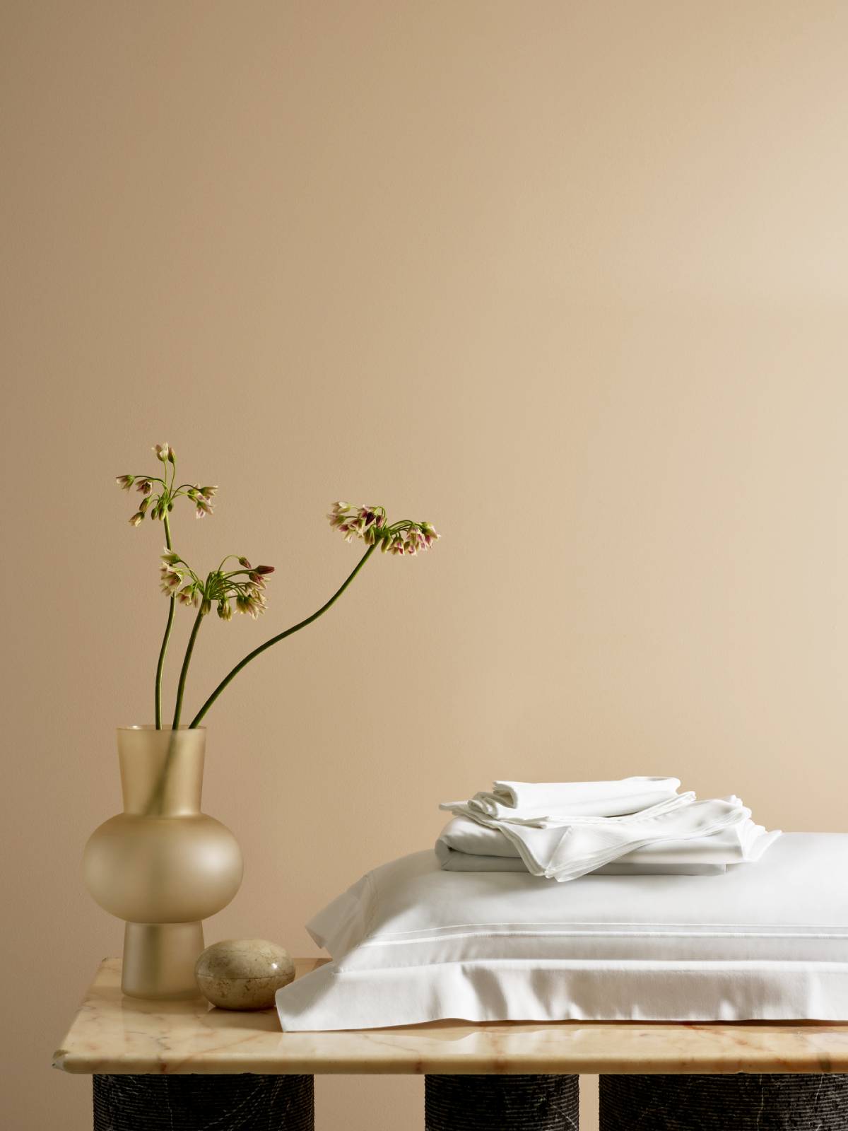 Flowers and Savoir bed linen beautifully arranged on a marble table against a pale yellow background