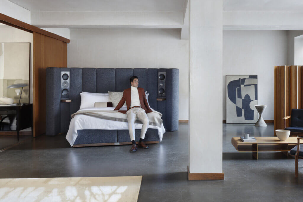 Our Seventy Five bed featuring a man resting at the foot of the bed, dressed in white and brown clothing, which complements the blue, white and brown colours of the bed.