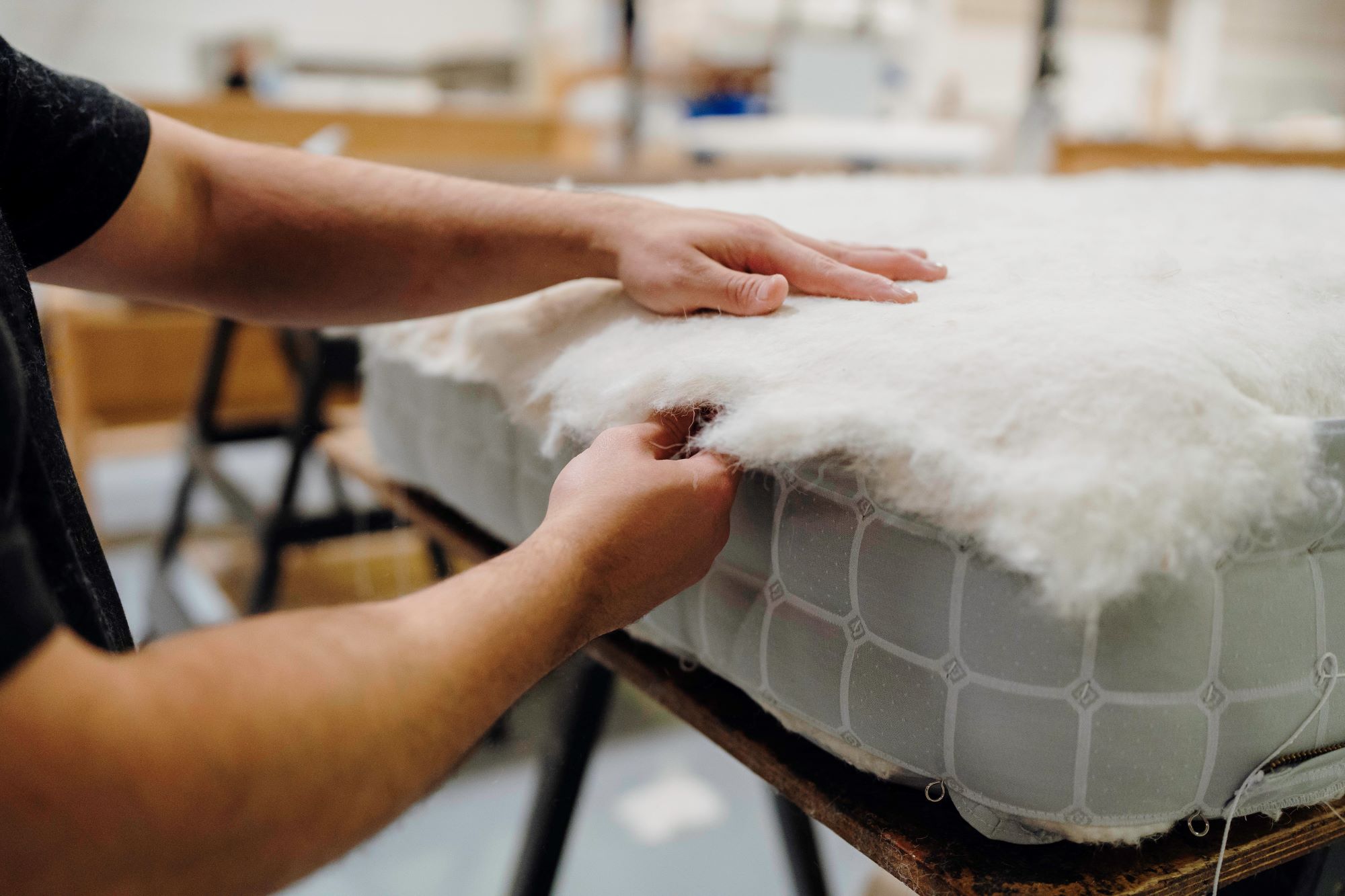 Image of a craftsman preparing a mattress with natural materials