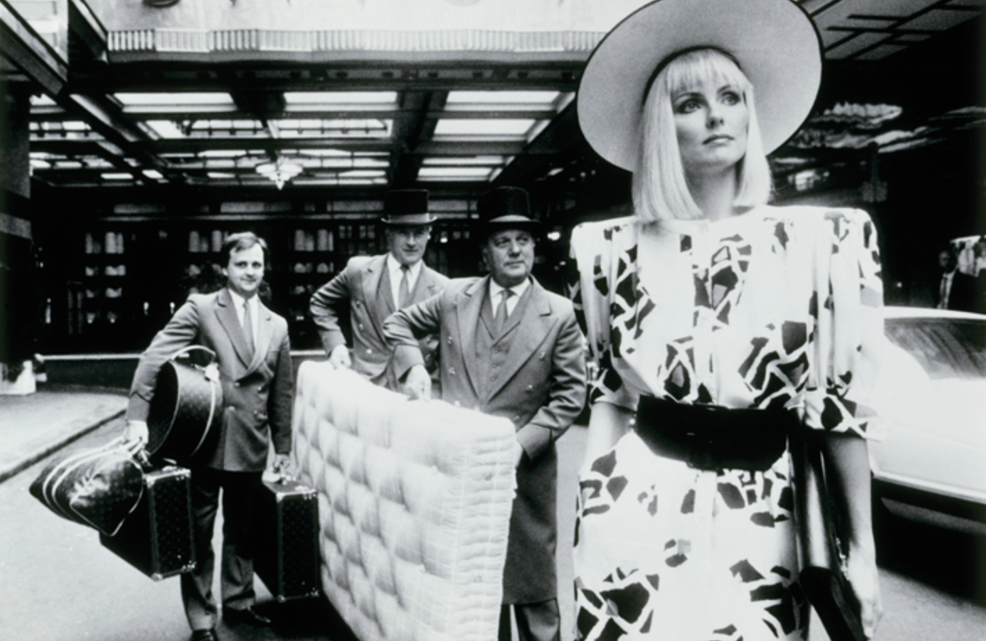 black and white image of a Lady with a Savoir Bed in background carried by 3 men